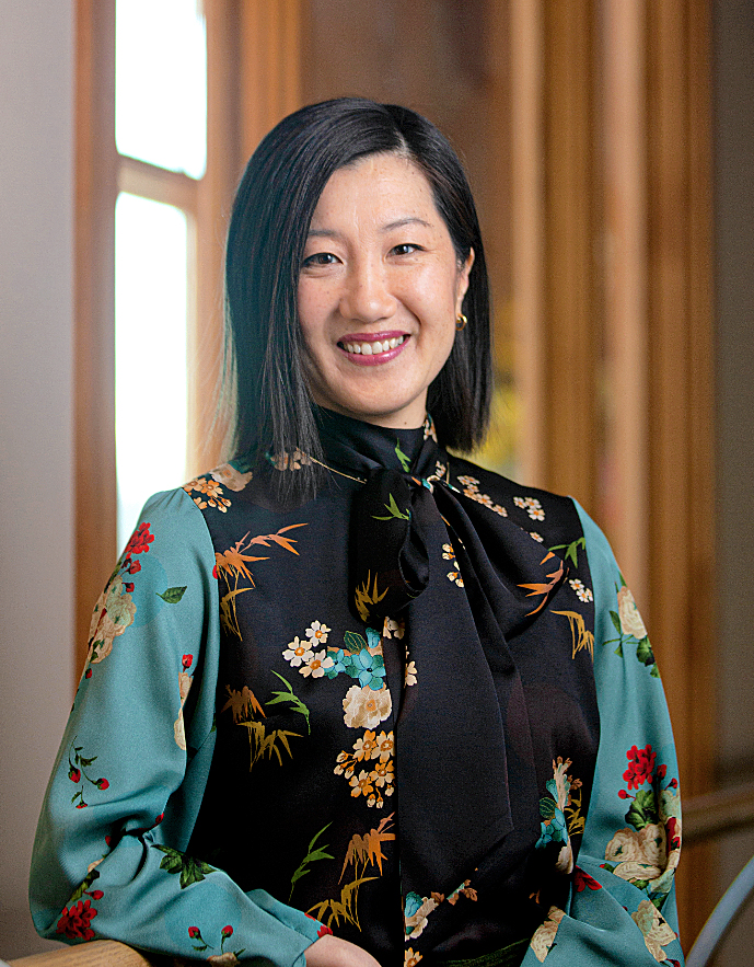 Female with dark hair wearing floral shirt while smiling at the camera
