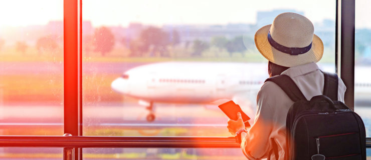 female wearing sun hat staring out a window at an airplane