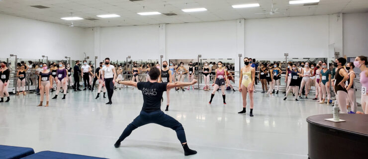 male instructor leading a large group of dancers in a studio