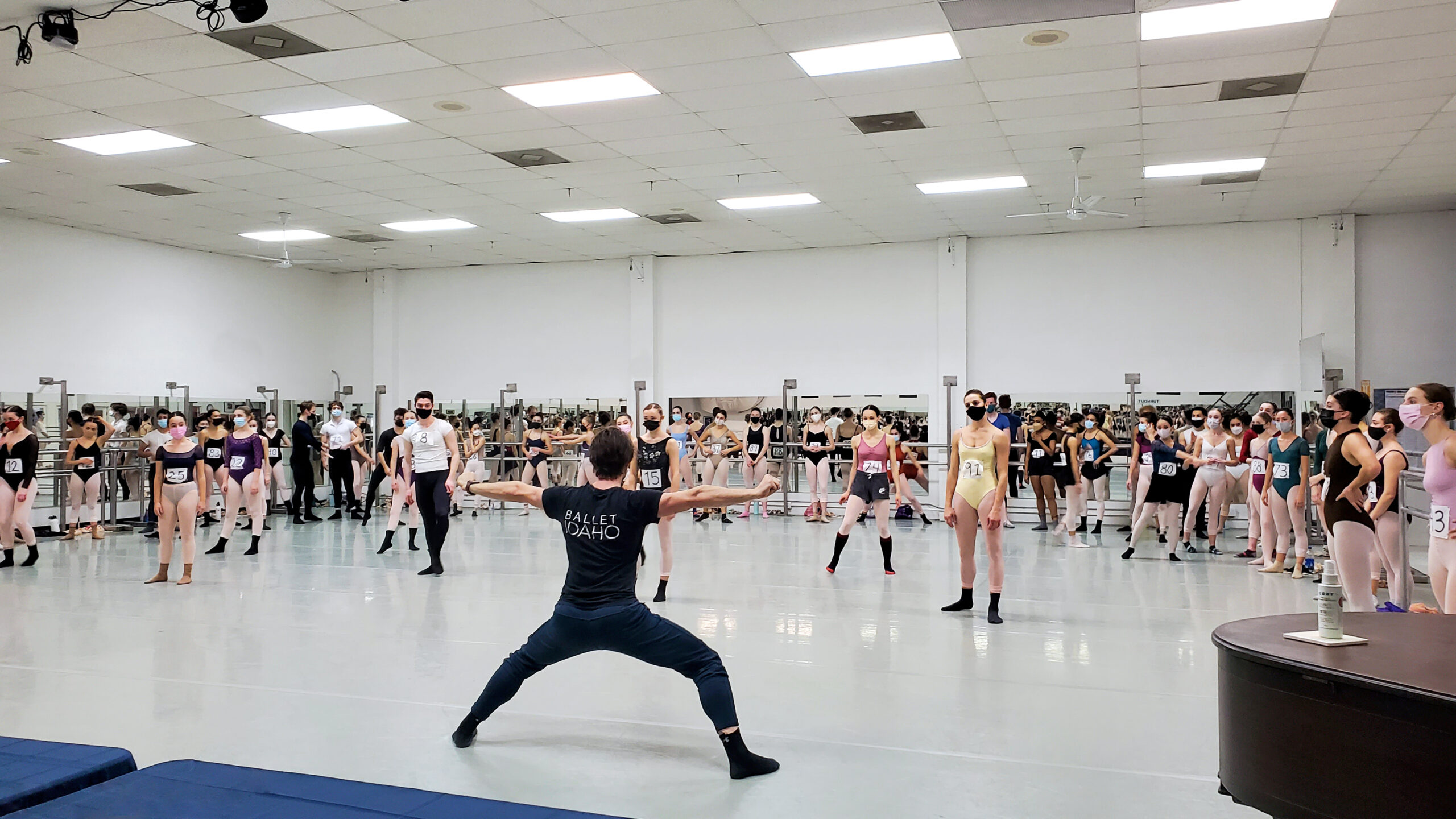 male instructor leading a large group of dancers in a studio