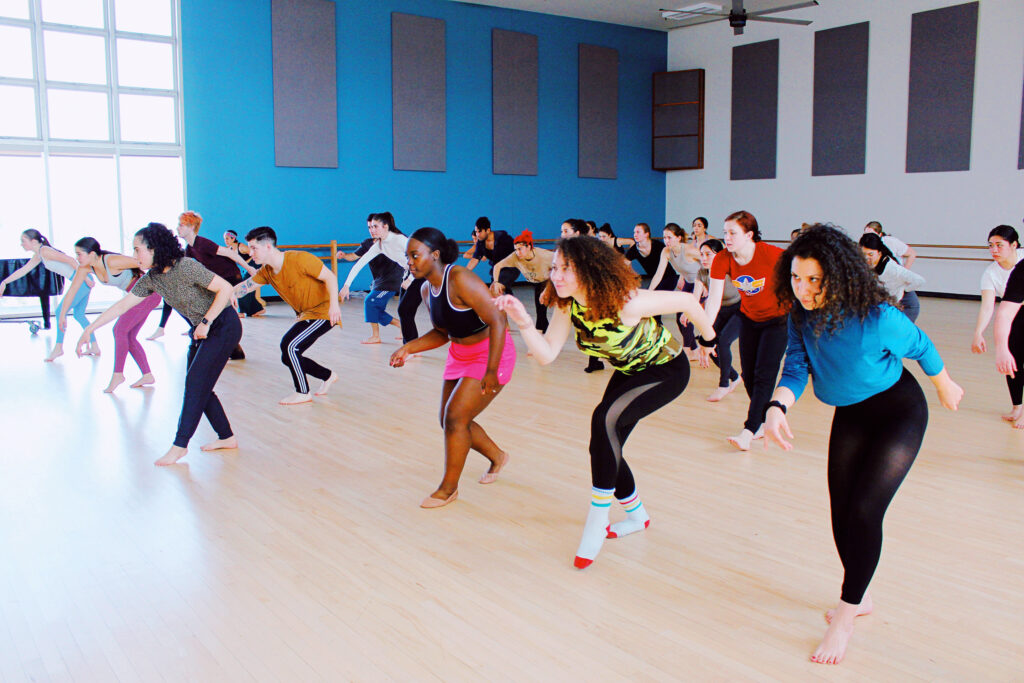 a large group of students dancing in spacious studio