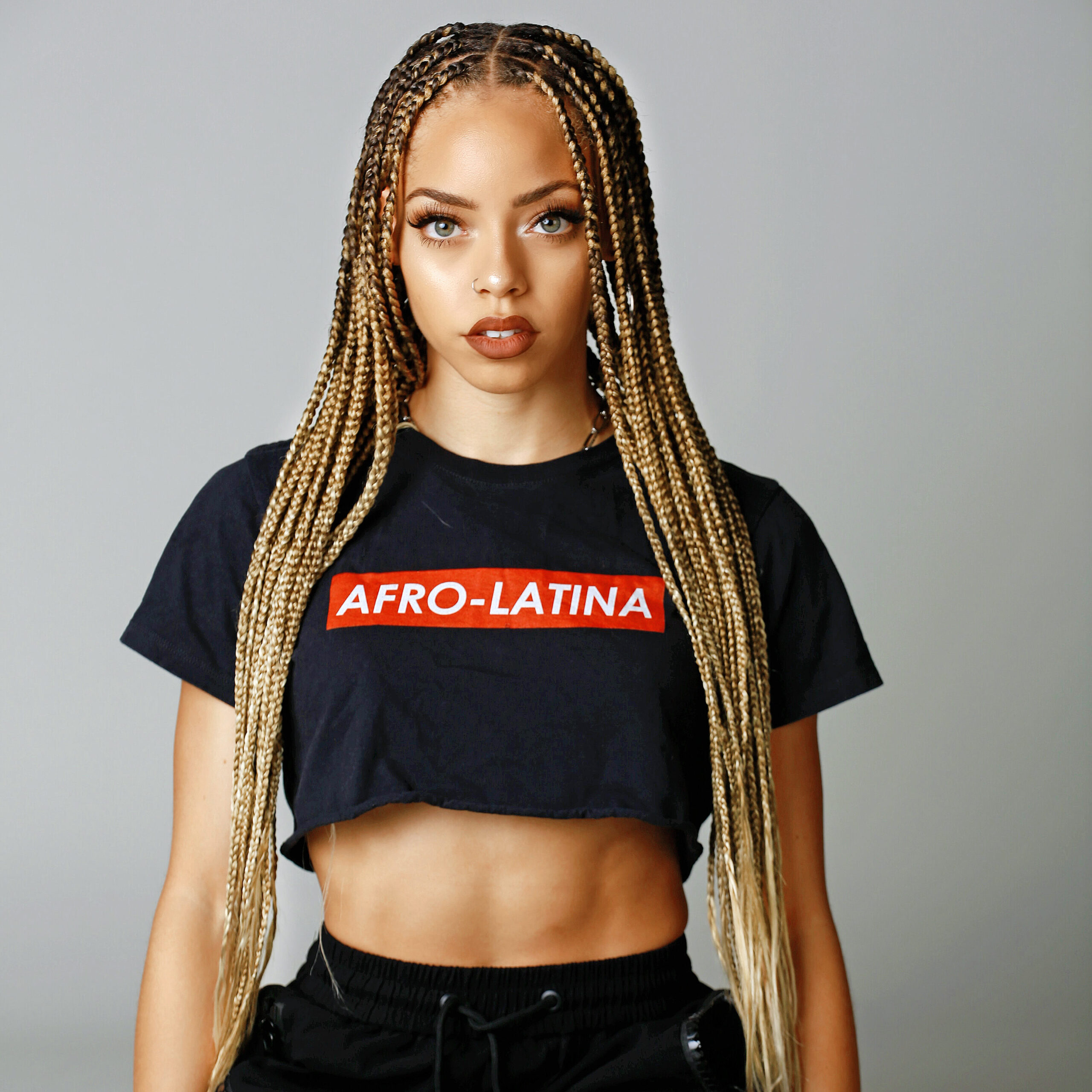 female with blonde braids wearing a black t shirt with the words "Afro-Latine"