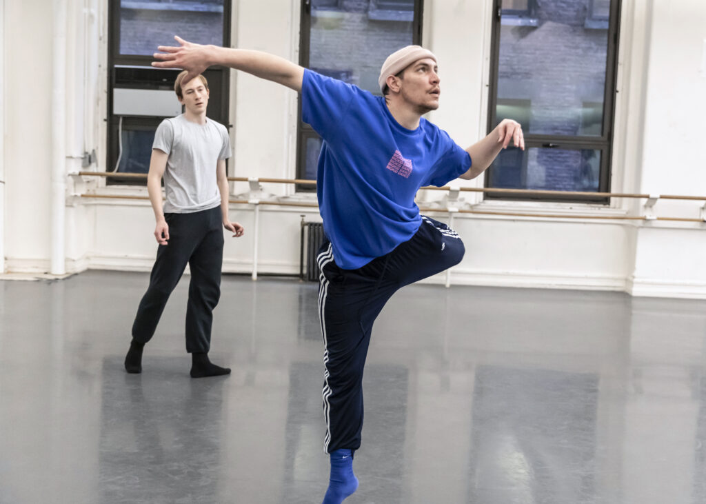 male choreographer leaping with arms out and one leg behind