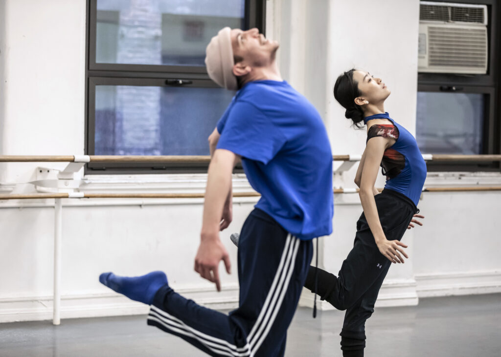 male choreographer and female dancer standing on leg, the other bend behind them with backs arching 