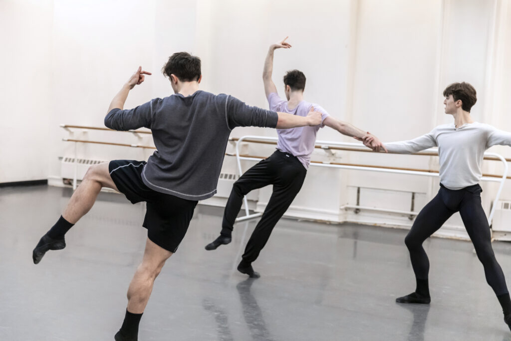 male choreographer dancing next to two male dancers