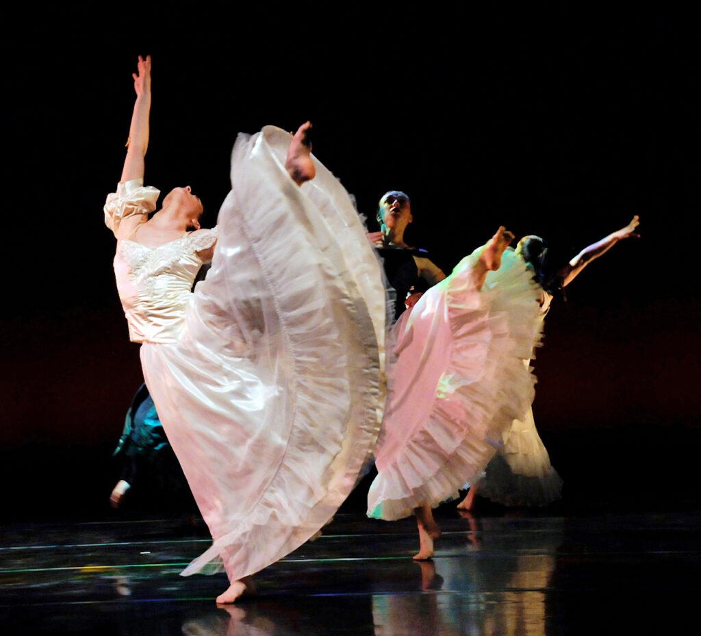 female dancers wearing long white skirts extending their leg to the side