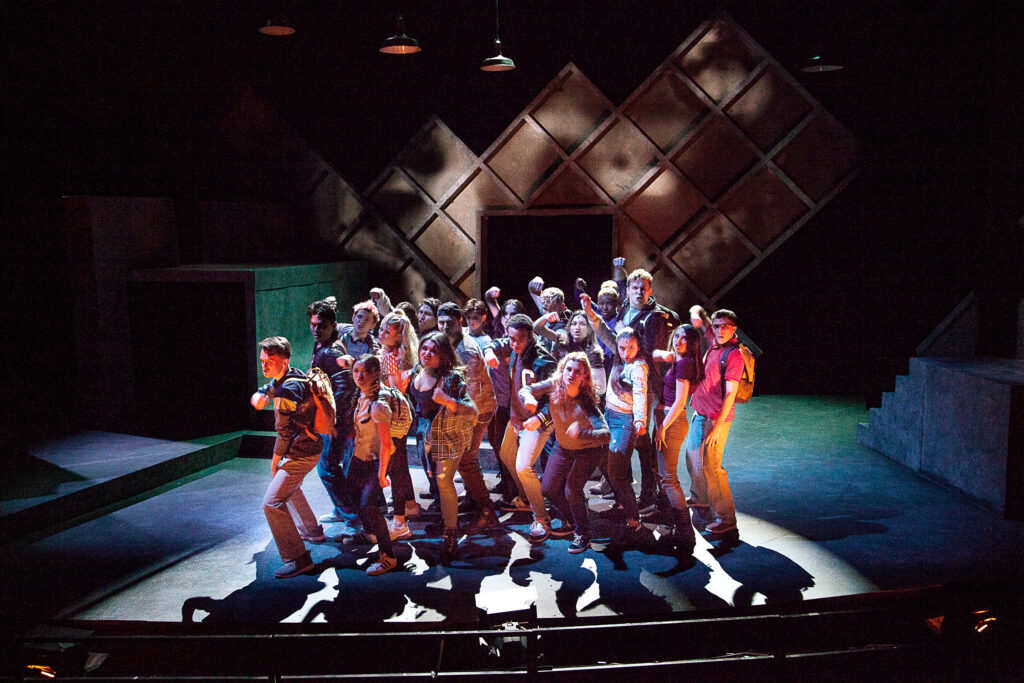 a large group of performers clumped together center stage