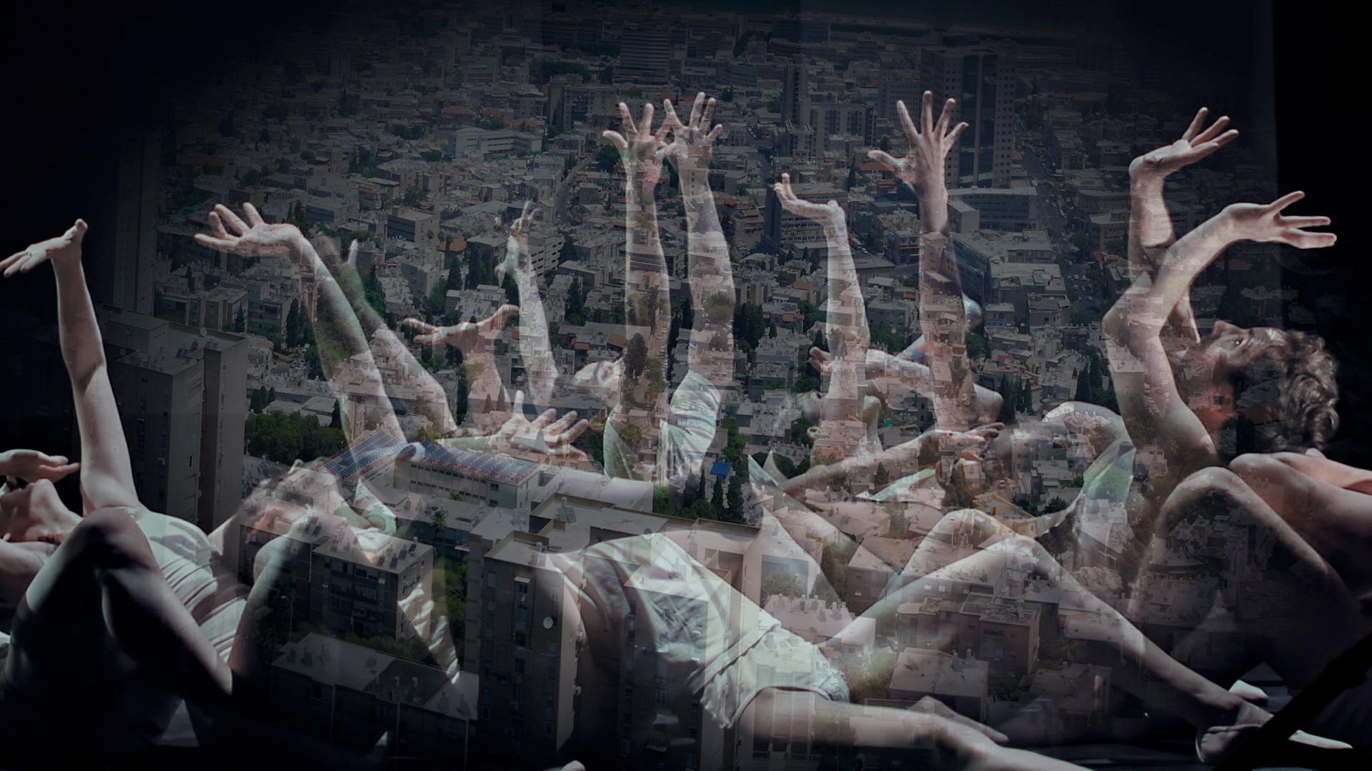 A group of dancers on the floor looking and reaching up with outstretched hands.