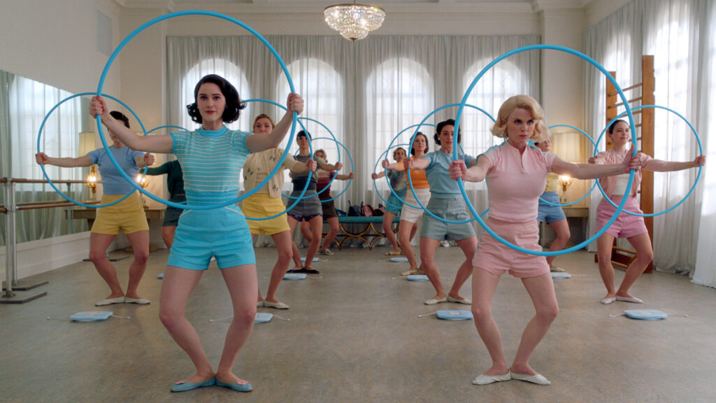 a large group of women holding a hula hoop out in front of them while standing in first position plie