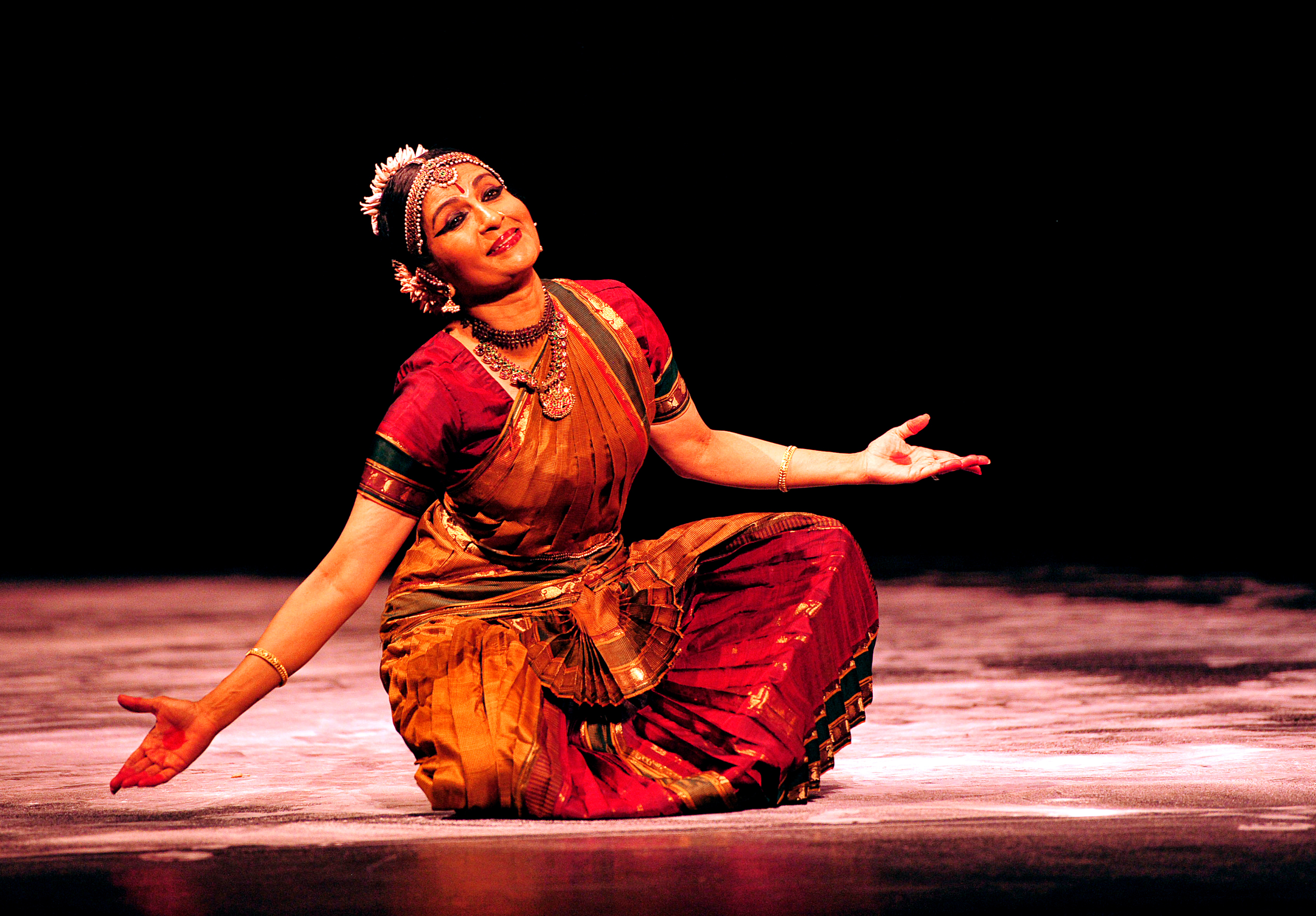 female on stage wearing traditional bharatanatyam clothing.