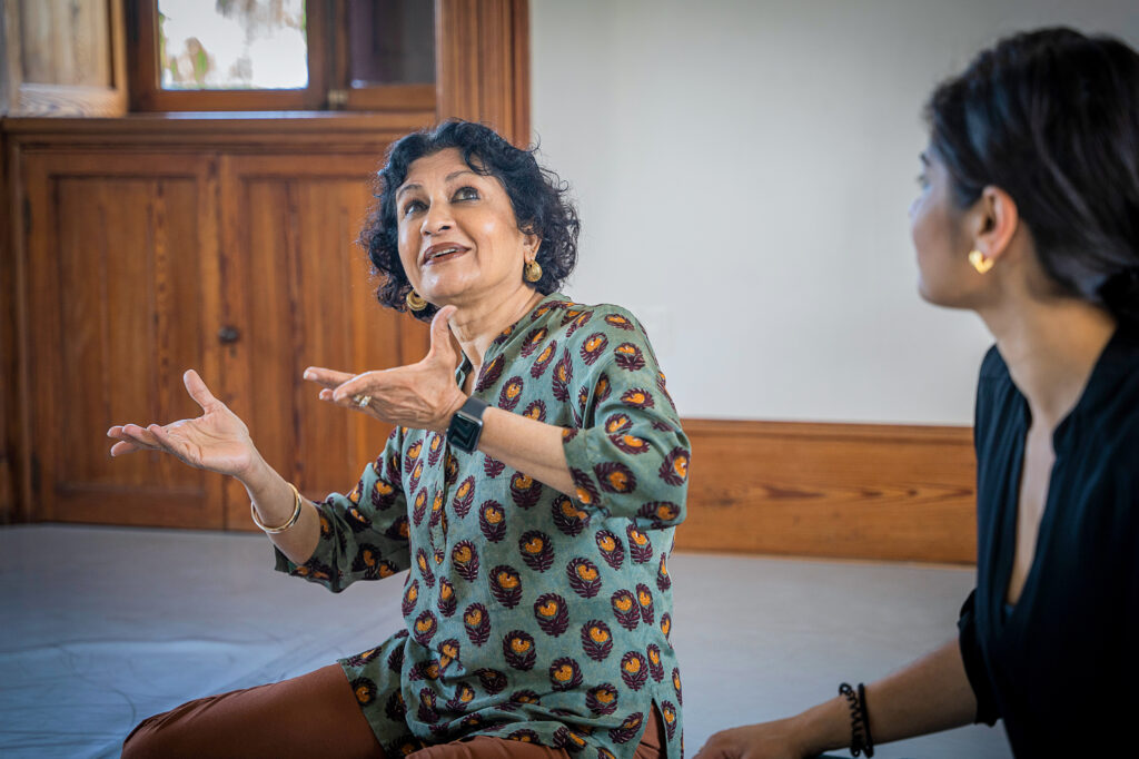 female sitting on floor and gesturing with hands