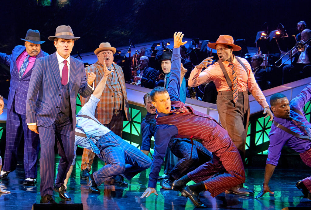 male performers wearing suits and hats, center dancer is hinging backwards