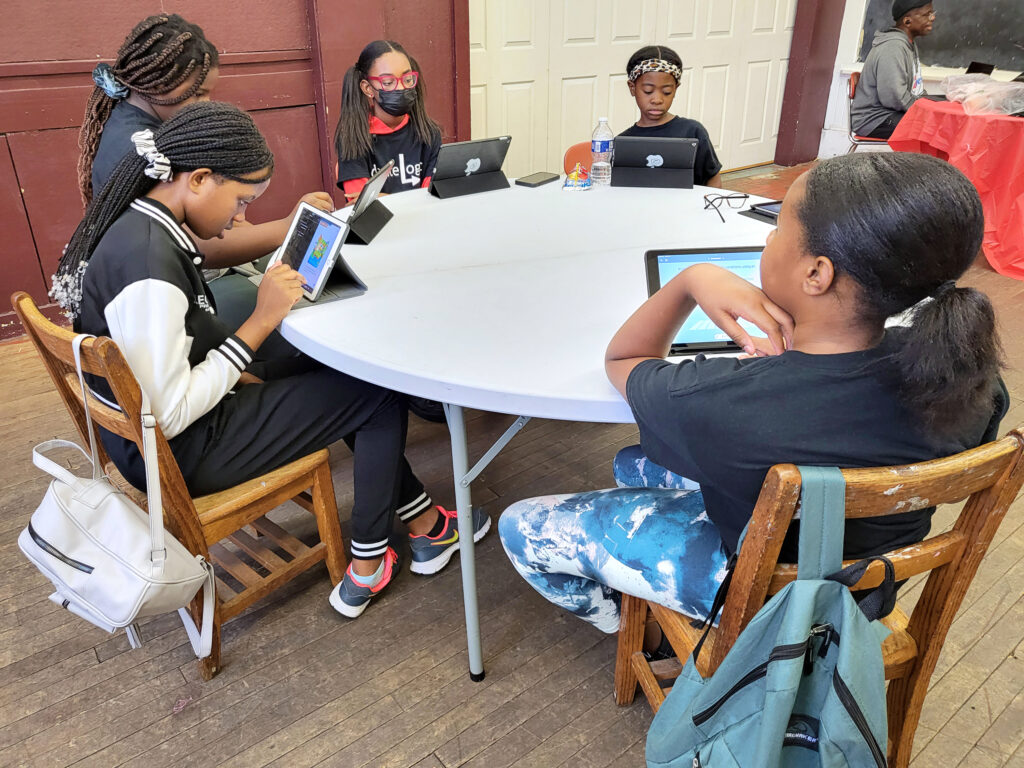 female students sitting around a table working on iPads
