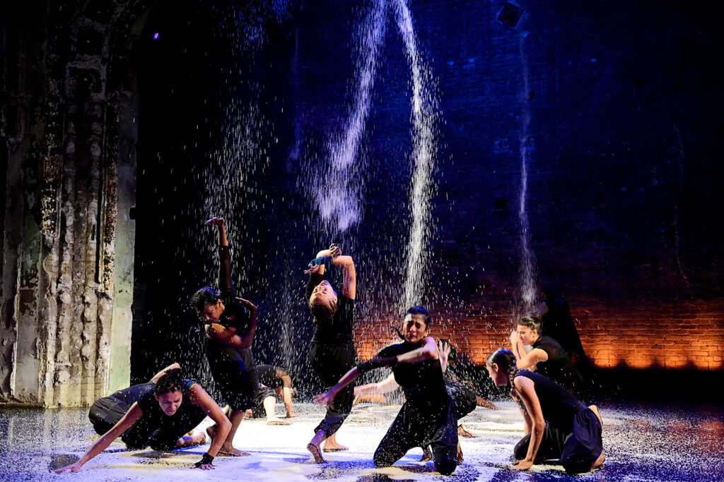 a large group of dancers performing while rice is falling from above