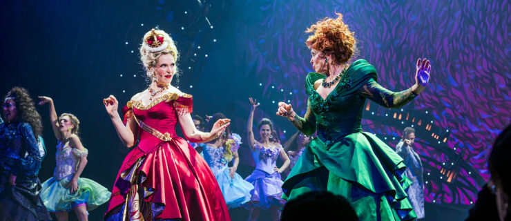 two females wearing big ball gowns staring at each other center stage