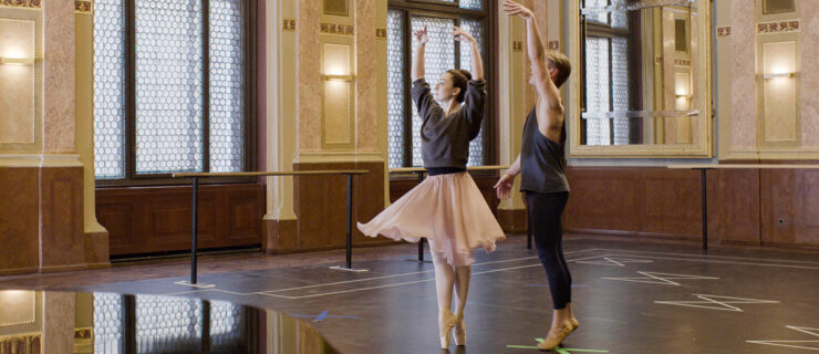 In a still from "FBI: International," Madison Keesler poses in sous-sus on pointe, arms in high fifth. Her partner stands just behind her, one arm upraised as though he had just released her hands. They were practice clothes and are in a beautiful studio, a piano visible in the foreground.