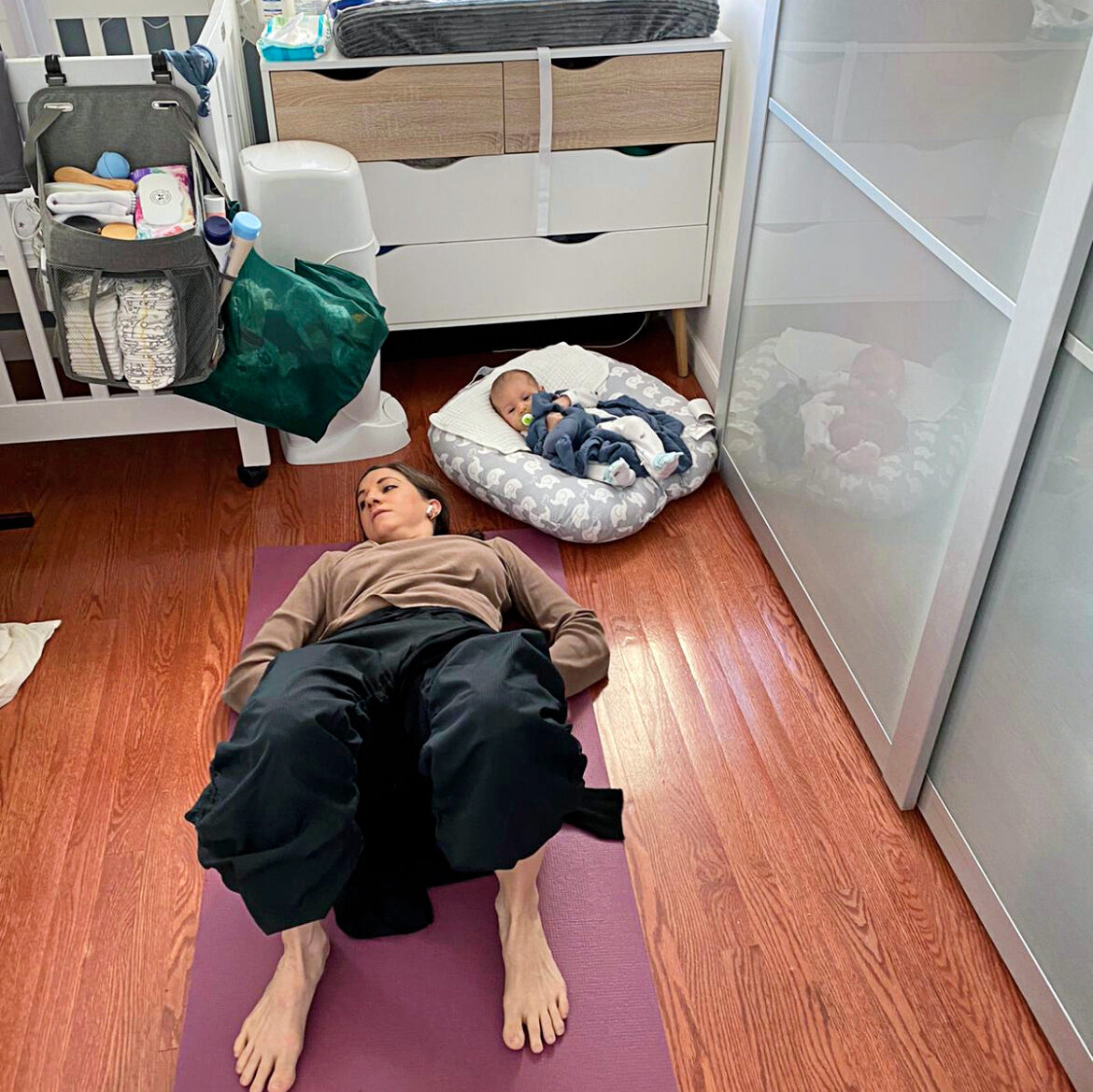 a woman on the floor in a nursery doing pilates next to her baby