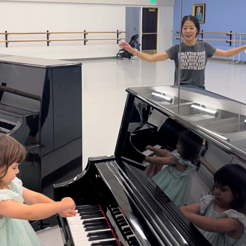 a little girl wearing a blue dress playing the piano in a studio 