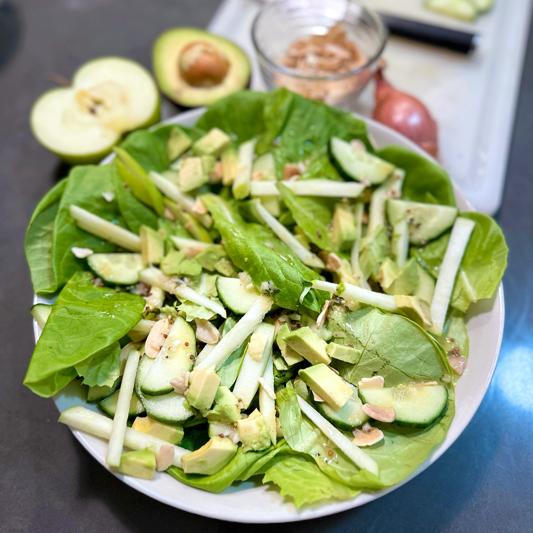 a salad with cucumbers, avocado, and apple on top