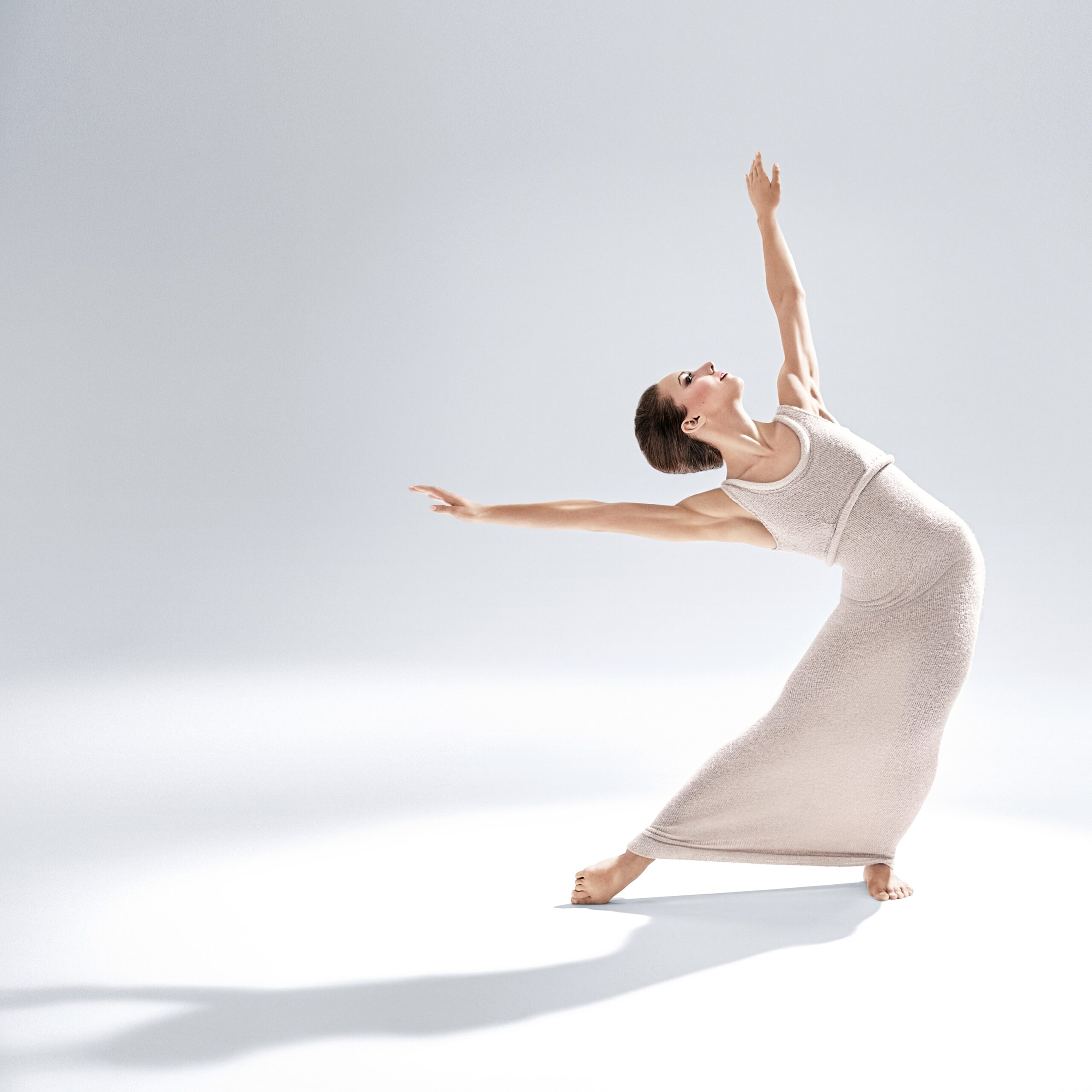 a female dancer wearing an ankle length white dress hinging from her wait with her arms out wide