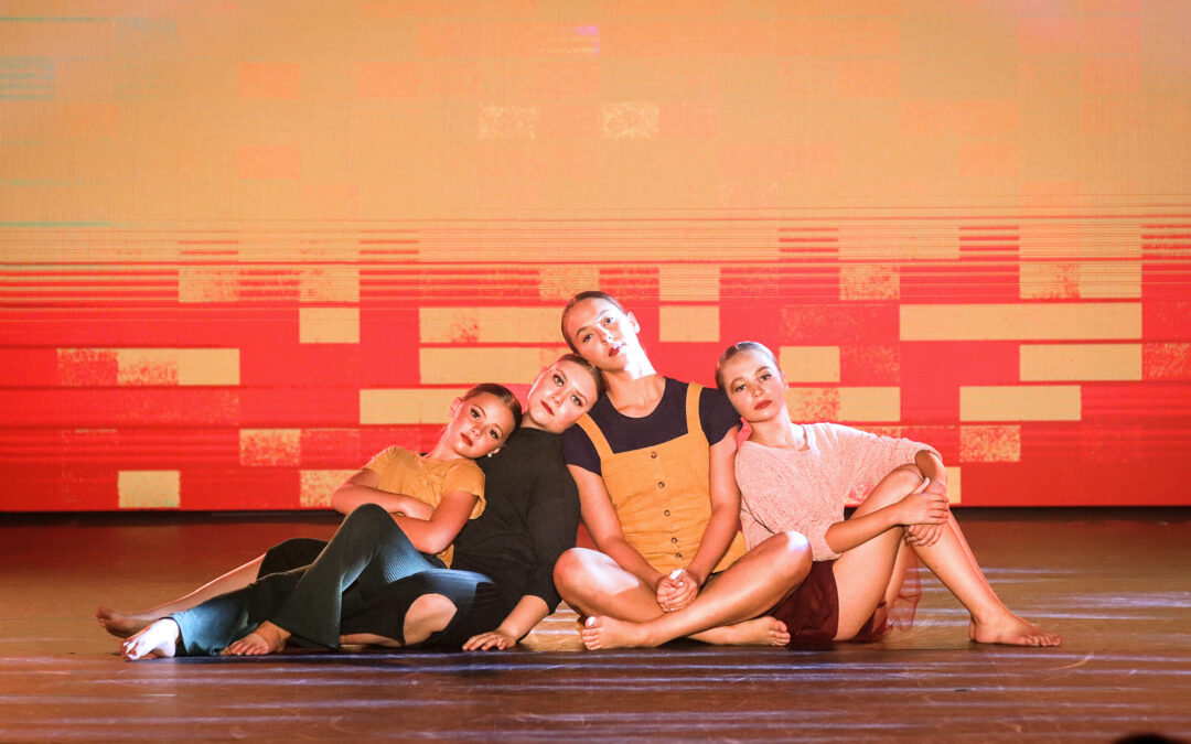 4 dancers sitting on the floor leaning against each other