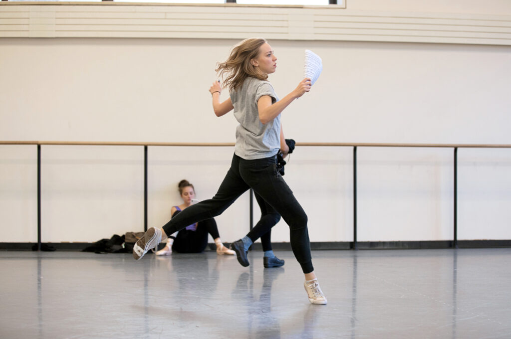 a dancer holding a paper rehearsing in a studio 