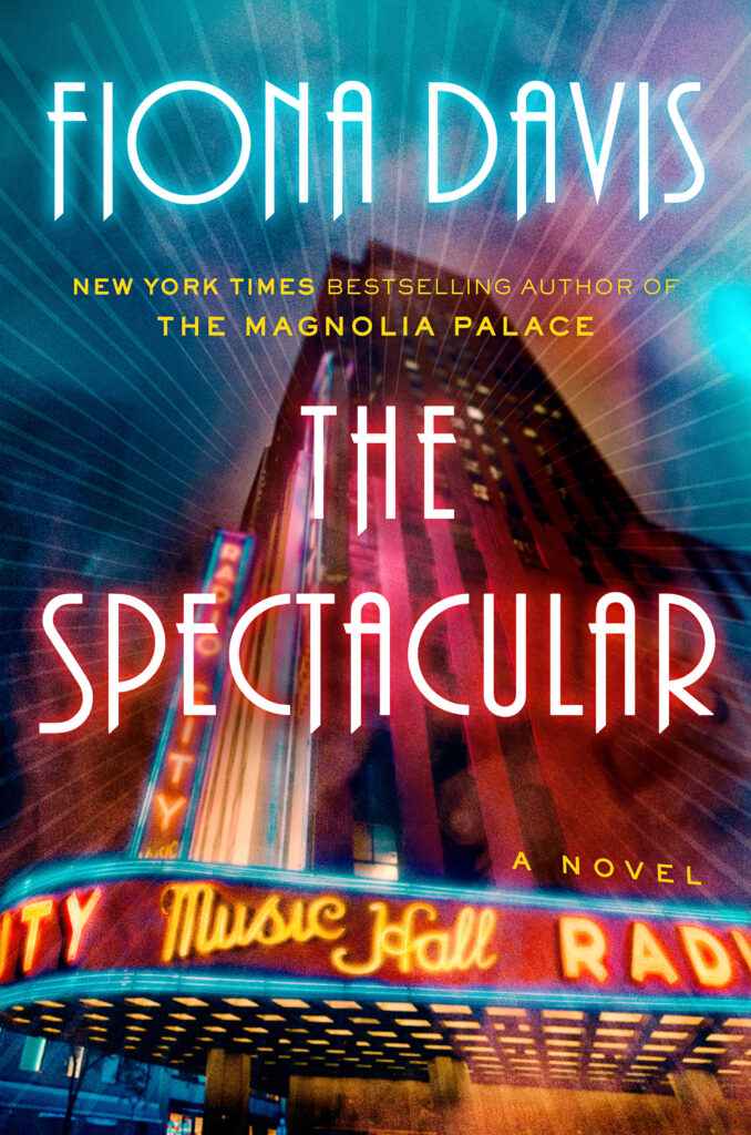 An image of Radio City Music Hall is washed in neon light. Splashed across in neon letters is "Fiona Davis, New York Times Bestselling Author of The Magnolia Palace" and beneath it, "The Spectacular."