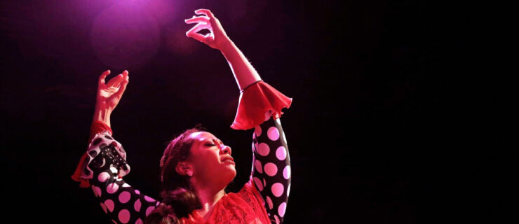 a female dancer onstage lifting her arms over her head with fingers precisely placed