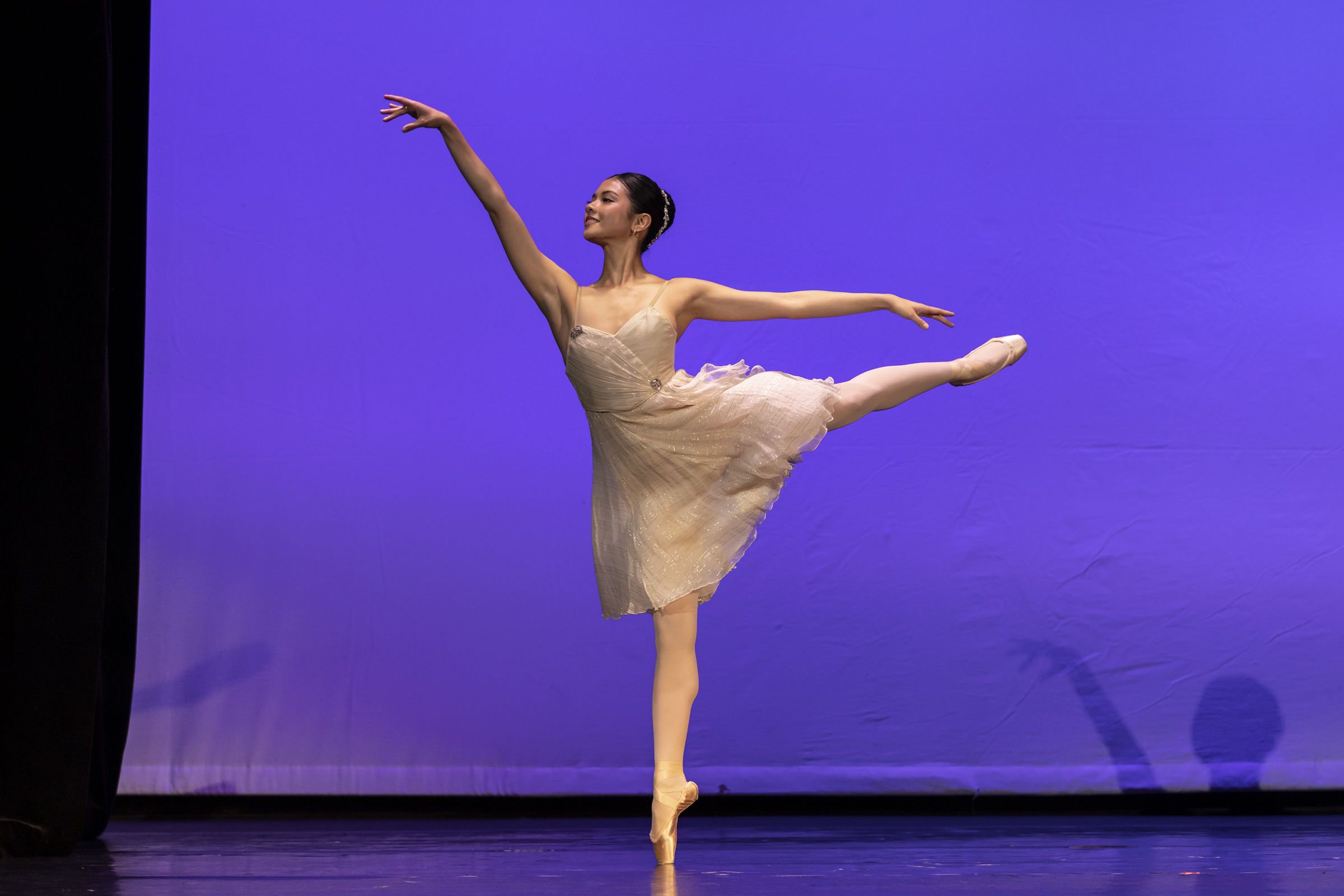 Mikaela Santos performs a variation from "La Talisman." She does an arabesque on pointe in a cream-colored, flowing dress.