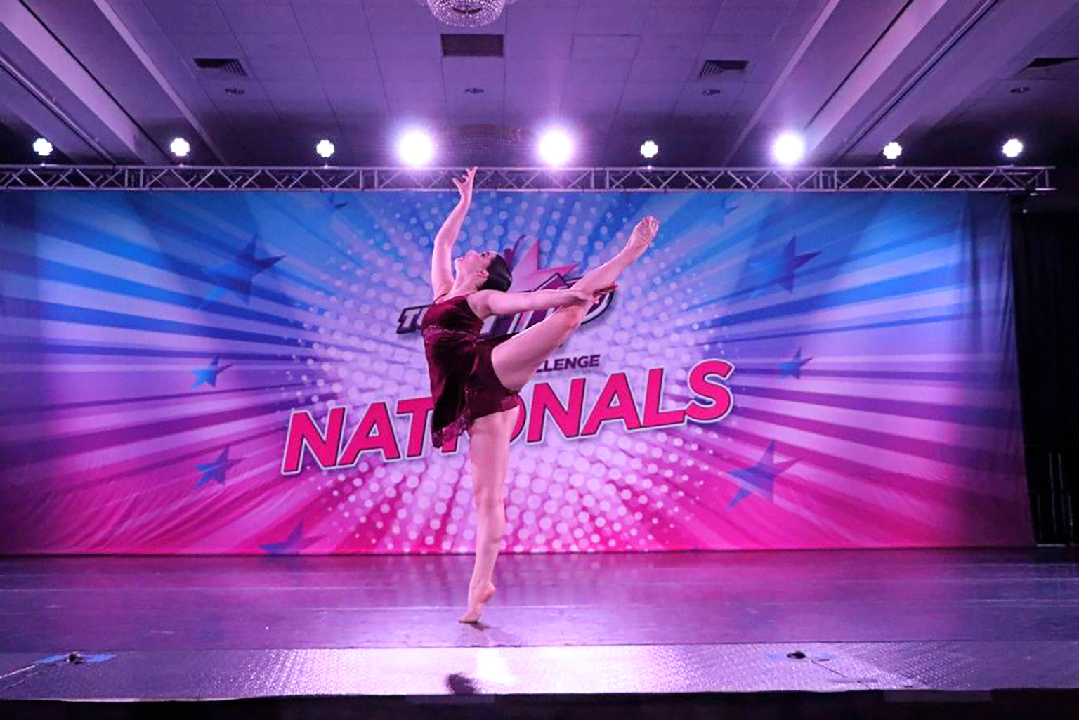 a dancer performing an arabesque on stage at nationals