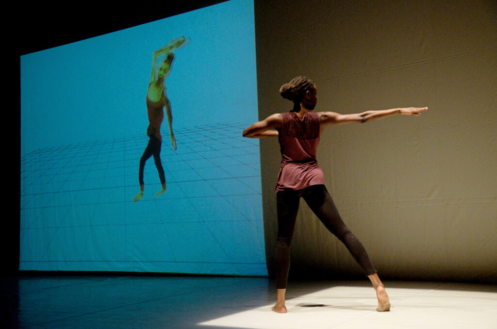 a dancer performing next to a video projection