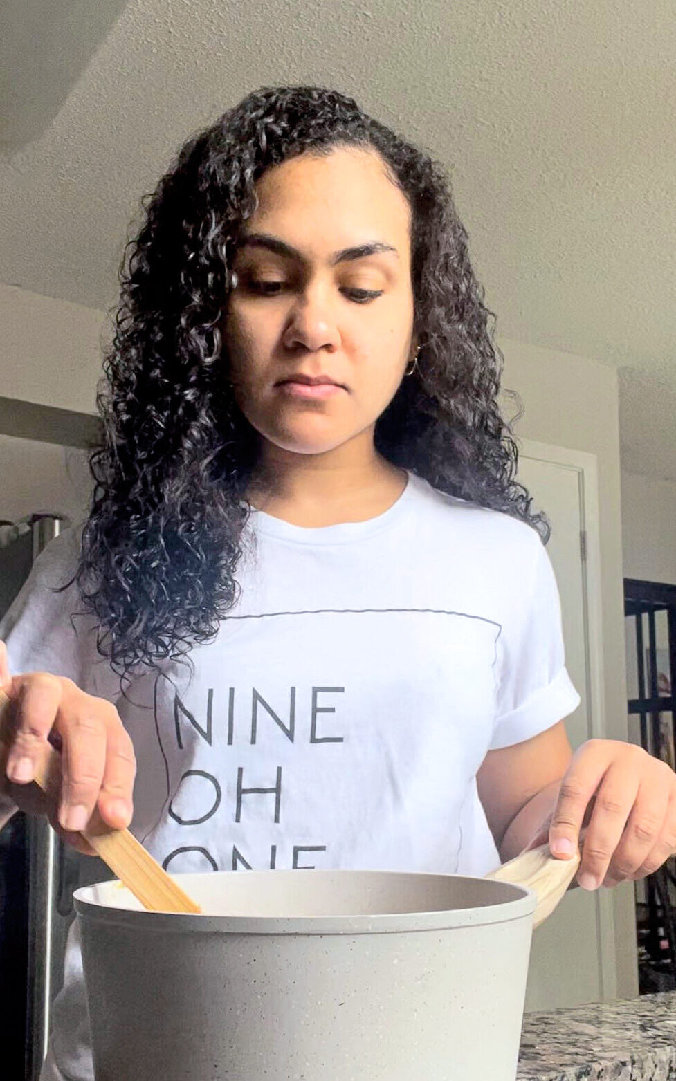 a female wearing a white shirt stirring a pot with a wooden spoon