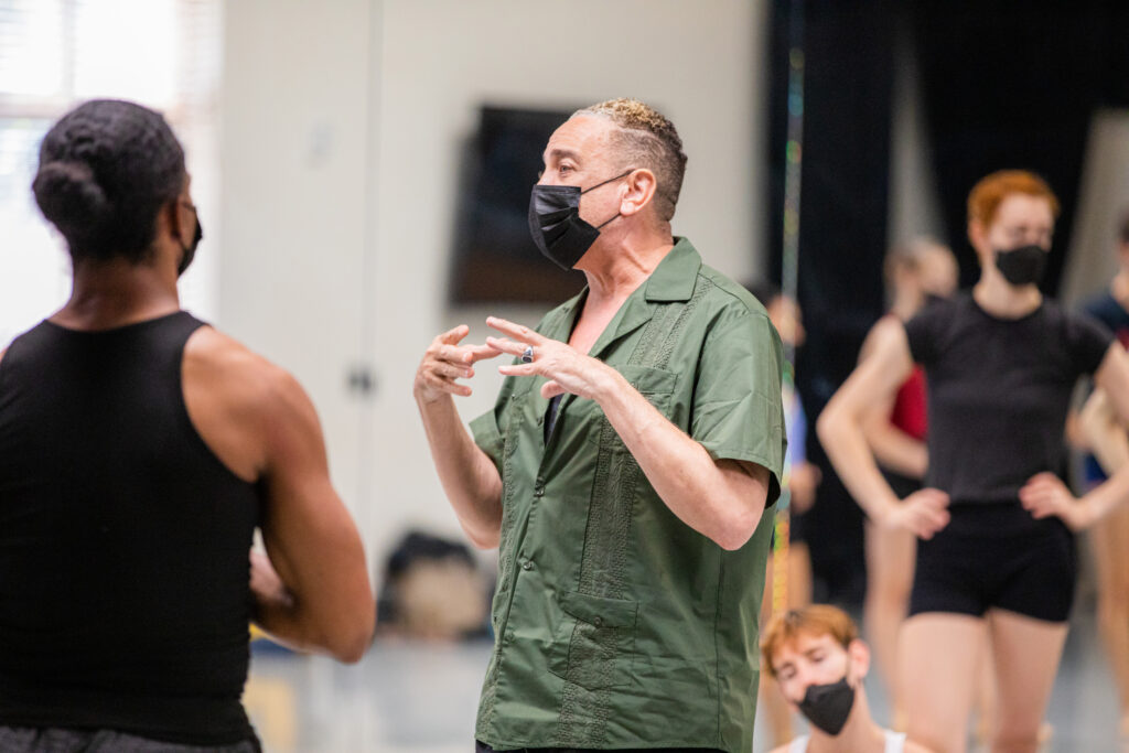a male choreographer talking to dancers in a studio