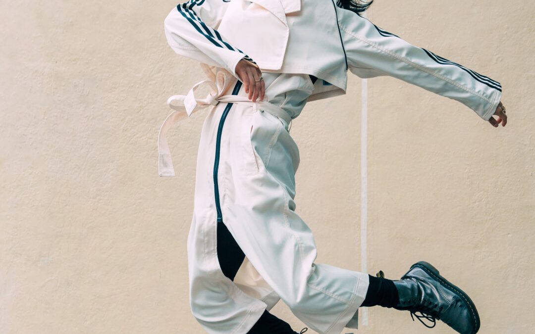 a woman wearing a white track suit jumping in the air