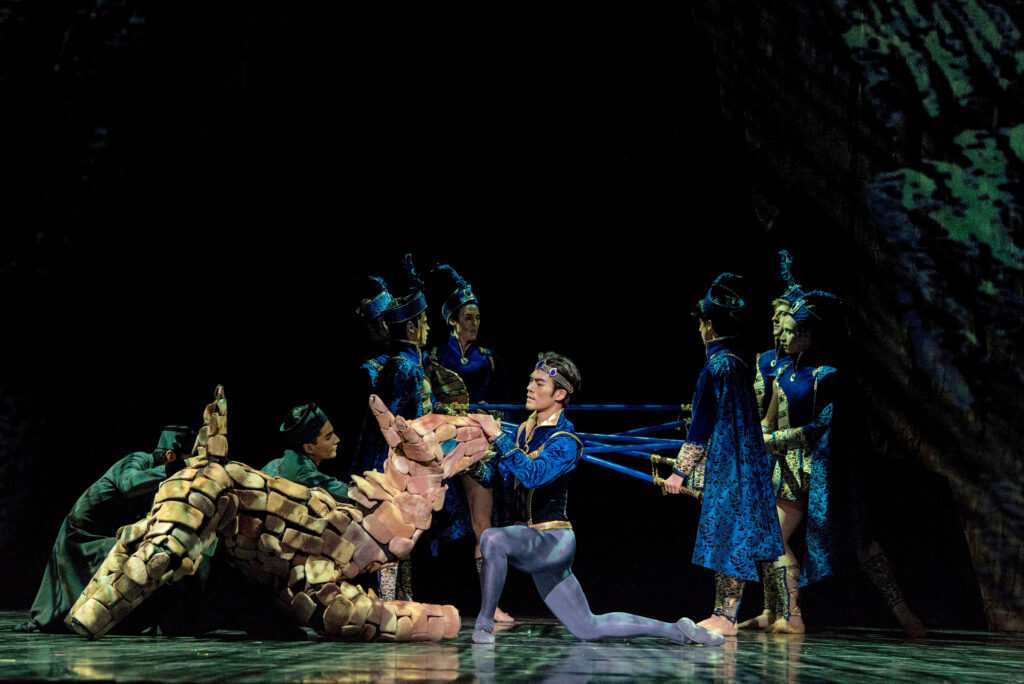 a male dancer petting a large animal puppet 