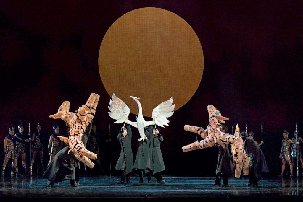 dancers holding large animal props on stage 