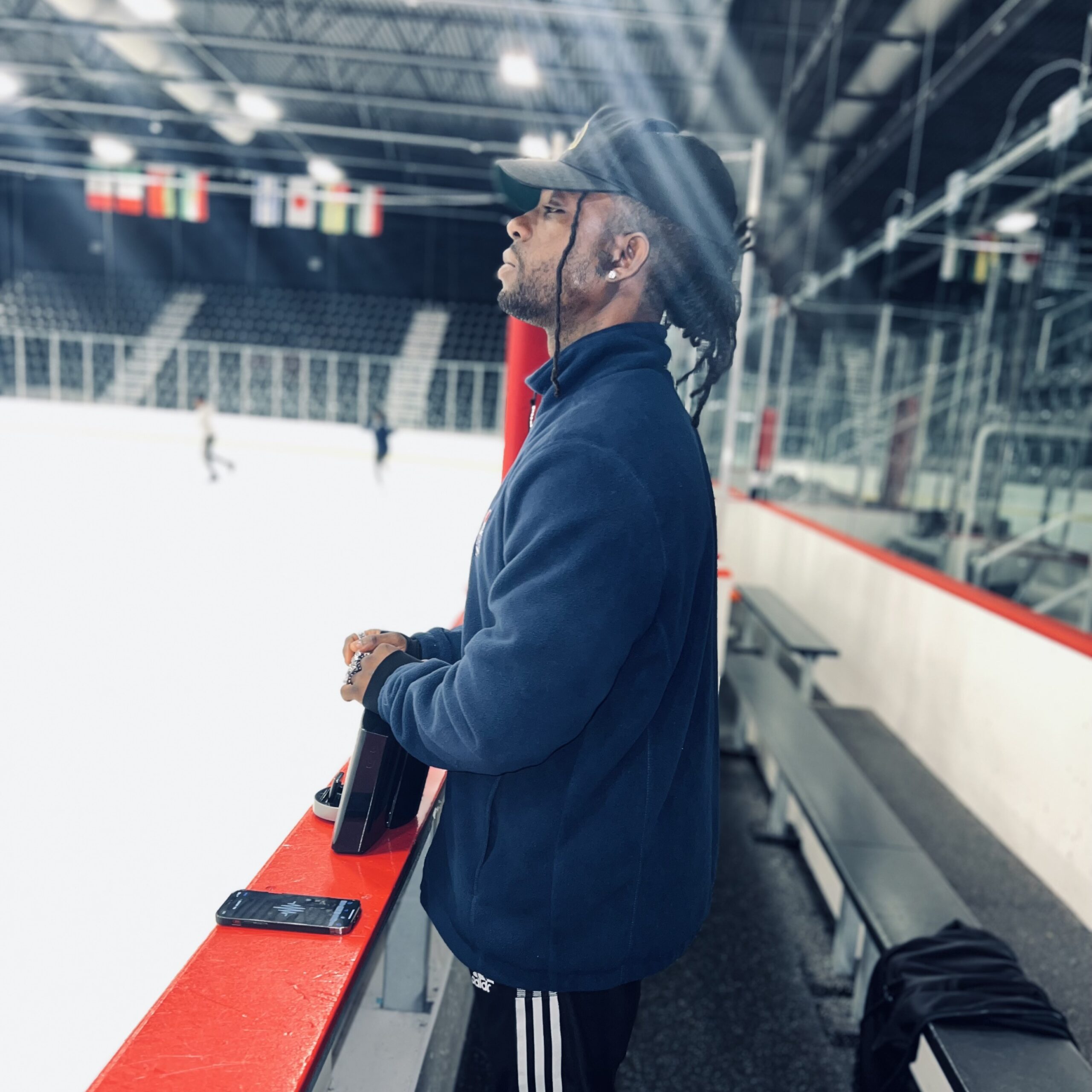 a male coach standing at the edge or rink