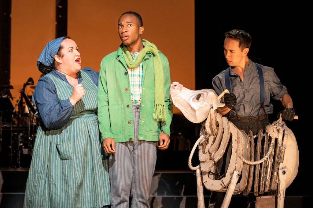 3 actors standing next to a cow puppet 