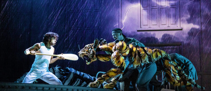 a tiger puppet fighting an actor holding an oar