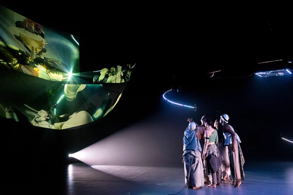 Dancers performing slowdanger's SUPERCEll from left to right: Jasmine Hearn, Taylor Knight, Anna Thompson, kira shiina, Nile Harris Group of figures with backs to audience focusing on suspended fabric