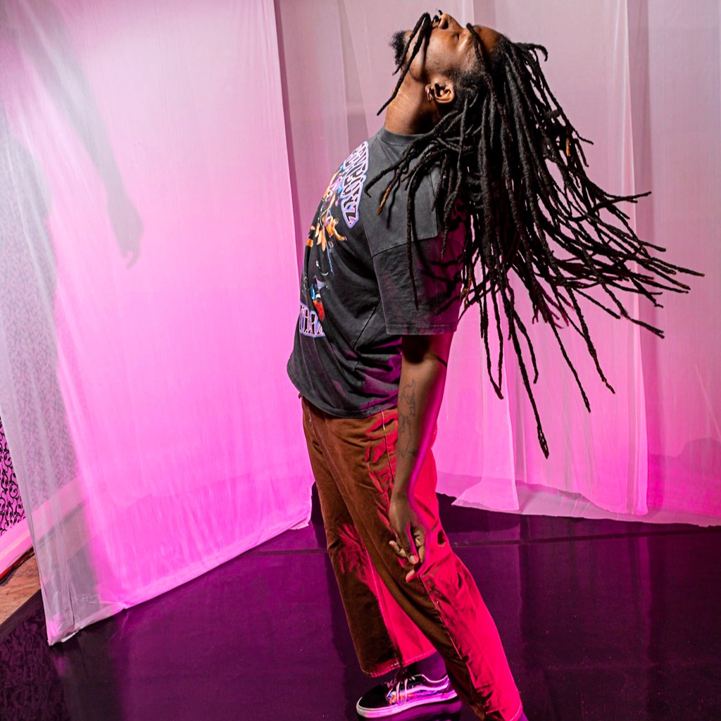 a male dancer looking up with long braids flipping back