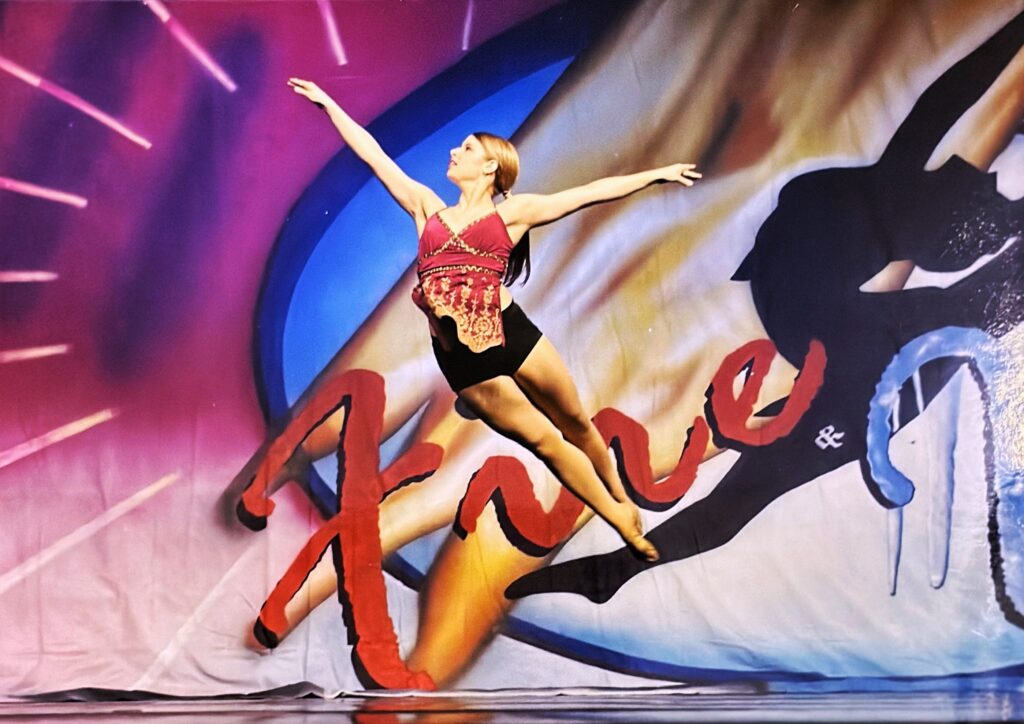 a dancer mid-air on stage at a competition 