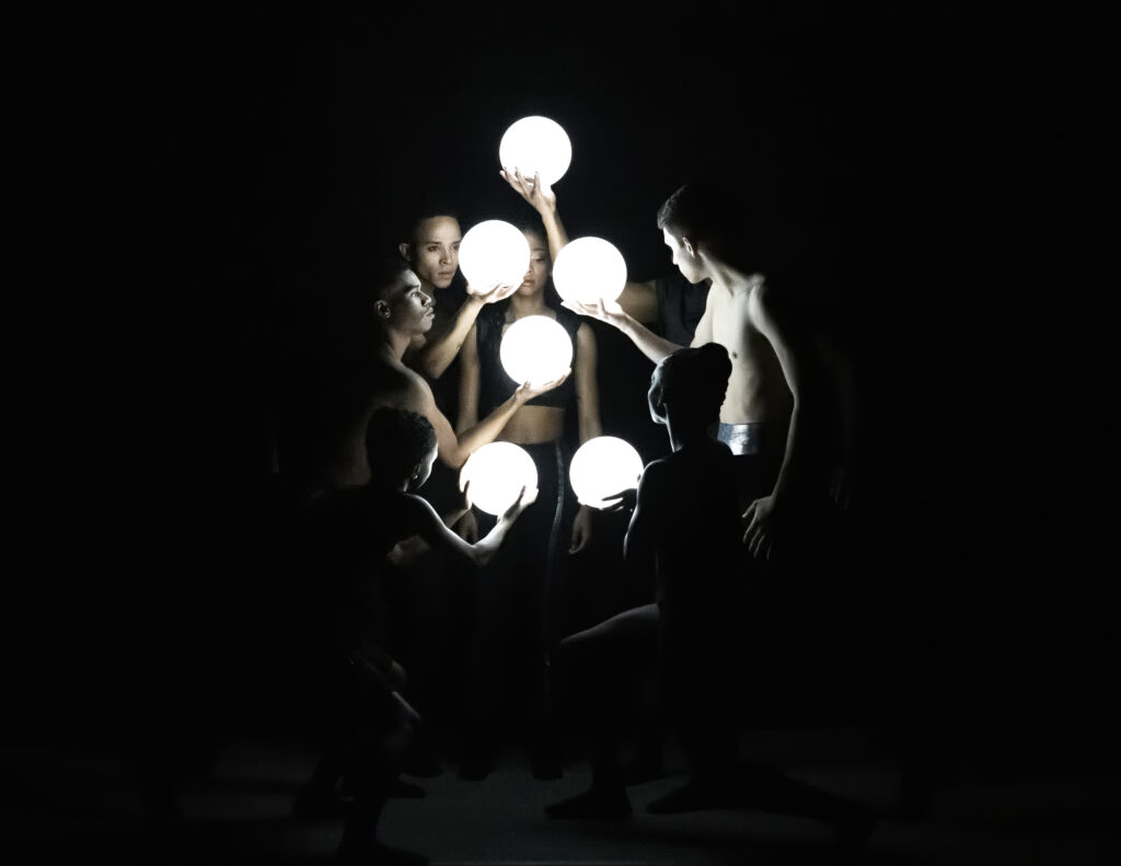 dancers on stage holding glowing orbs
