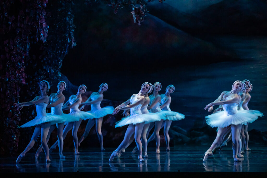 a large group of dancers wearing white tutus on stage