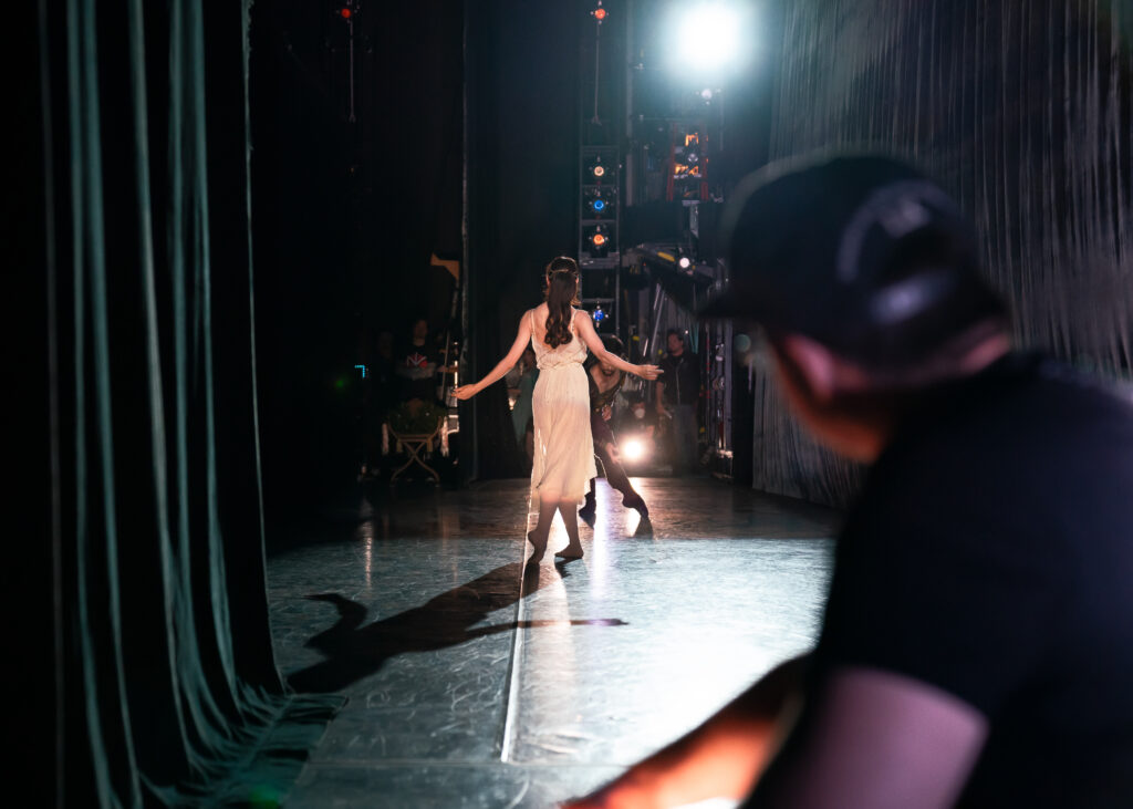 a view of onstage from the wings, a female dancer wearing white 