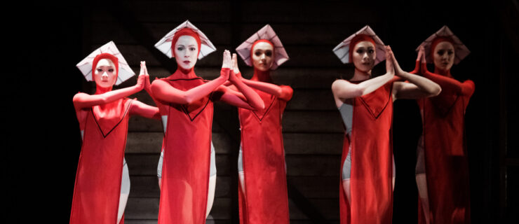 a group of female dancers wearing long red dresses and white hats