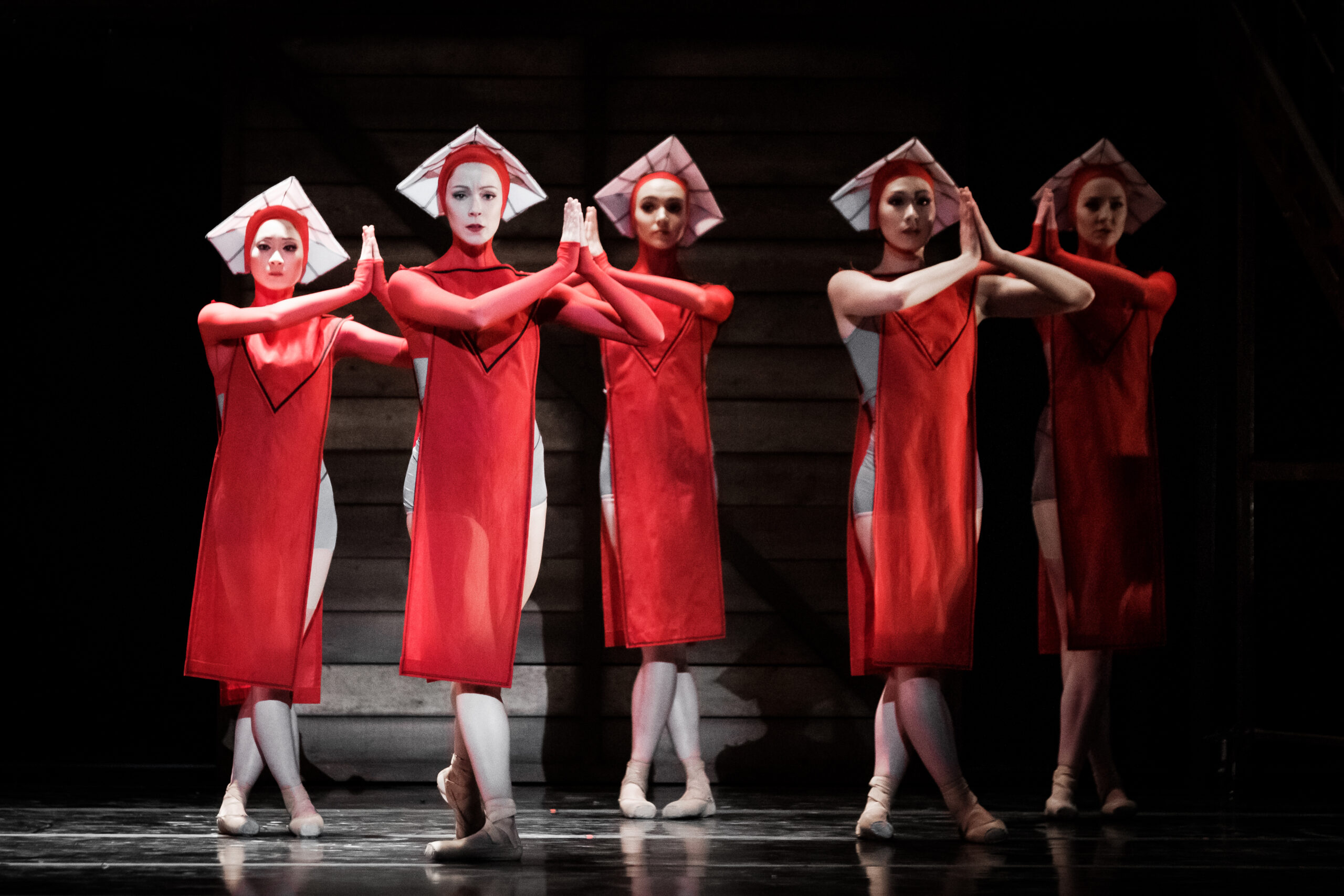 a group of female dancers wearing long red dresses and white hats
