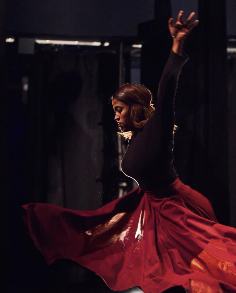 a female dancer on stage turning in a long red skirt