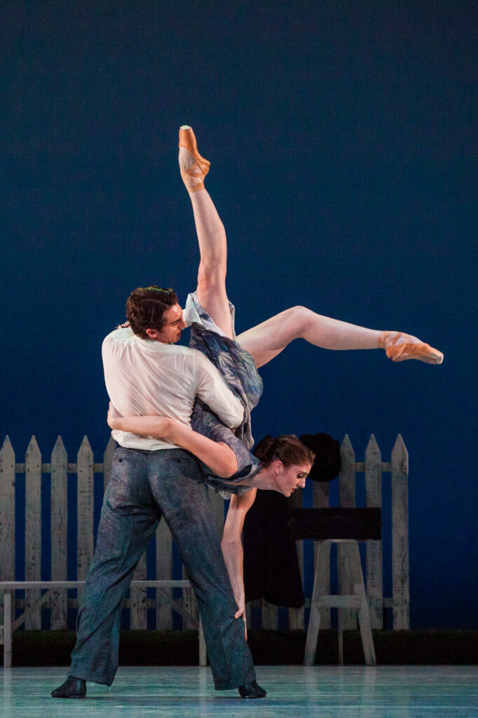 a male dancer holding a female dancer upside down with her legs extended 