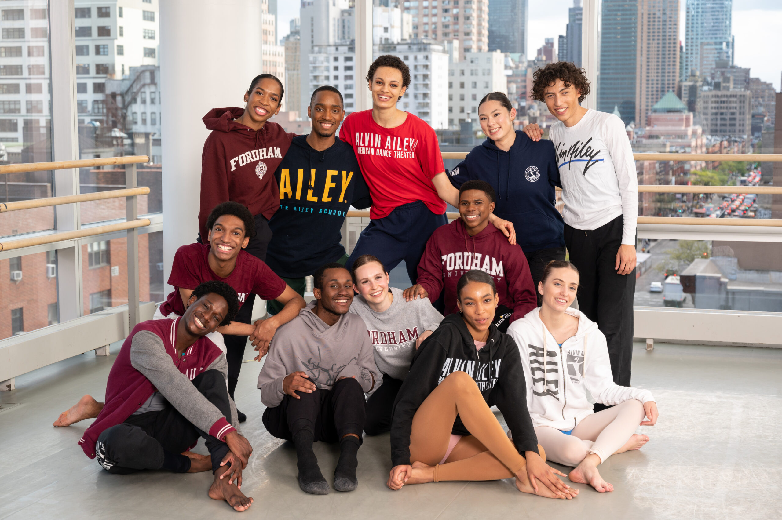 a group of dancers wearing Ailey/Fordham shirts smiling at the camera